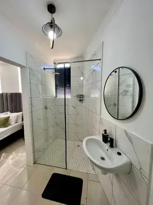 a bathroom with a shower and a sink and a mirror at Angel's Cottage in Paarl