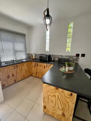 a kitchen with wooden cabinets and a black counter top at Angel's Cottage in Paarl