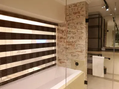 a bathroom with a tub and a stone wall at Misasa on Orchard in Cape Town