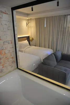 a mirror reflecting a bedroom with a bed and a couch at Misasa on Orchard in Cape Town