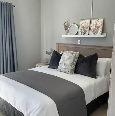 a bedroom with a large bed with black and white pillows at Fijnbos in Strand