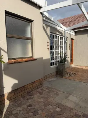 a white house with a window and a patio at Fijnbos in Strand