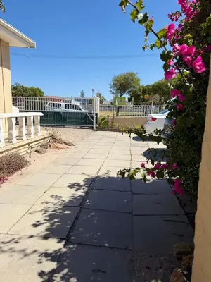 a sidewalk with pink flowers and a white fence at Home of peace self catering accommodation