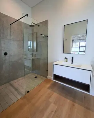 a bathroom with a shower and a sink and a mirror at Bird's Landing in Hermanus