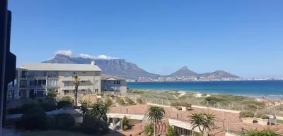 a view of the beach and the ocean with a building at Cozy Apartment with Table Mountain and beach views in Cape Town