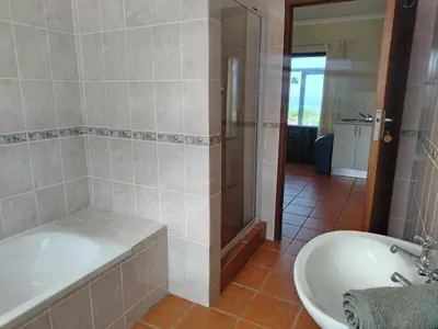 a bathroom with a shower and a tub and a sink at Starfish - The rockpool house in Bettyʼs Bay