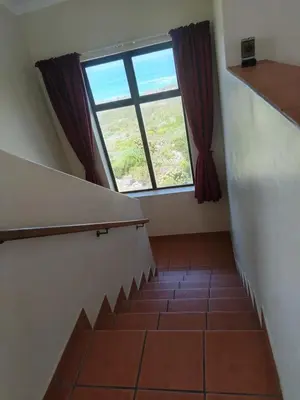 a staircase with a large window and red curtains at Starfish - The rockpool house in Bettyʼs Bay