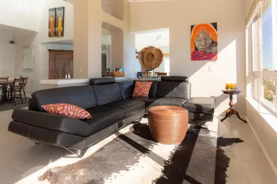 a living room with a black leather couch at Celtic Manor Boutique Guest House in Gordonʼs Bay