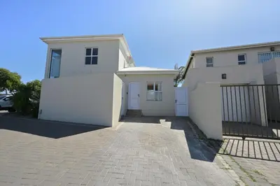 a white house with a gate and a driveway at The lodge in Cape Town