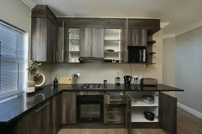 a kitchen with wooden cabinets and a black counter top at The lodge in Cape Town