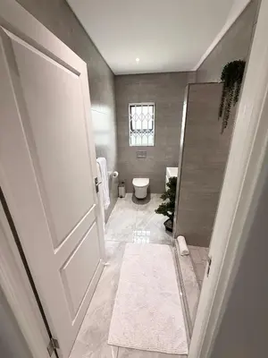 a bathroom with a toilet and a window and a door at Canal Walk Luxury 2 Bedroom Apartments in Cape Town