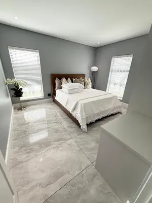 a bedroom with a large bed and two windows at Canal Walk Luxury 2 Bedroom Apartments in Cape Town