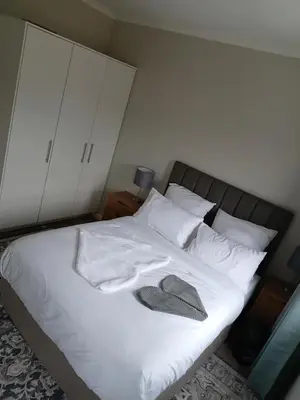 a bed with white sheets and a hat on it at Coastal Guest House with Free Parking and Braai Area in Cape Town