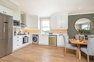 a kitchen with white cabinets and a wooden table at L'Ermitage Chateau and Villas at Villa 80 in Franschhoek
