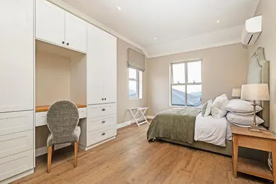 a bedroom with a bed and a desk and a chair at L'Ermitage Chateau and Villas at Villa 80 in Franschhoek