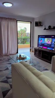 a living room with a couch and a flat screen tv at De Groove Luxury Homes in Cape Town