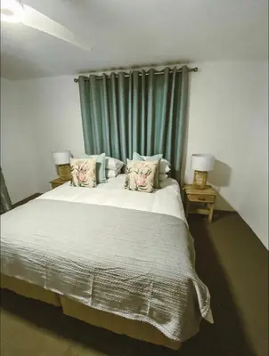 a bedroom with a large bed with a green curtain at Pura Vida Hermanus in Hermanus