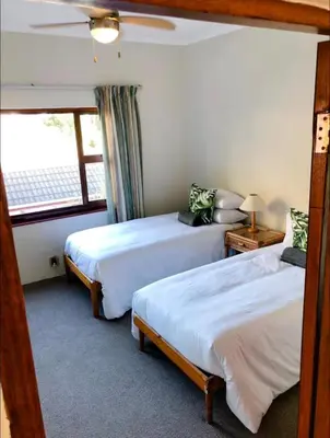 two beds in a room with a window at Pura Vida Hermanus in Hermanus
