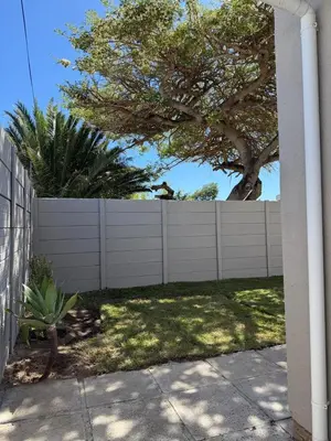 a white fence in a yard with a tree at Fijnbos Strand in Strand