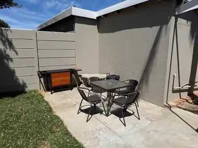 a patio with a table and chairs and a grill at Fijnbos Strand in Strand