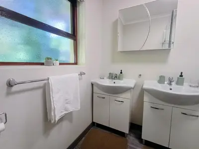 a white bathroom with two sinks and a window at GreenPeace in Stellenbosch