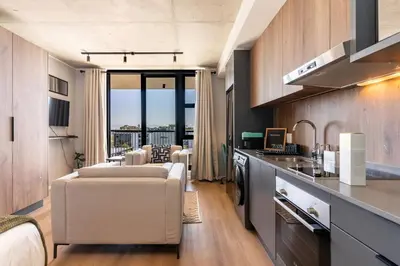 a kitchen and living room with a couch and a table at Stylish Executive Studio with Balcony in Riverlands, Observatory in Cape Town