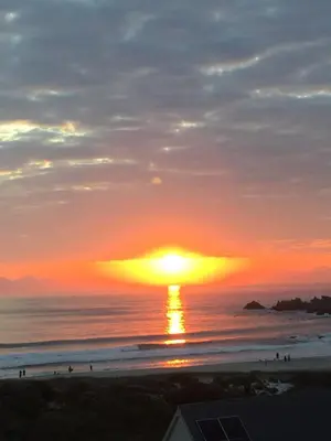 a sunset over the ocean with people on the beach at BEACH FRONT Side Studio, 50 steps to main beach in Pringle Bay