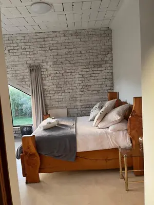 a bedroom with a large bed with a brick wall at BEACH FRONT Side Studio, 50 steps to main beach in Pringle Bay