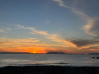 a sunset on the beach with the ocean at BEACH FRONT Side Studio, 50 steps to main beach in Pringle Bay