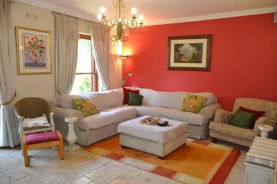 a living room with red walls and a couch and chairs at Cape Dutch Family Home in the Winelands in Somerset West