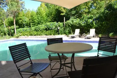 a table and chairs next to a swimming pool at Cape Dutch Family Home in the Winelands in Somerset West
