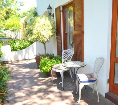a patio with two chairs and a table at Cape Dutch Family Home in the Winelands in Somerset West