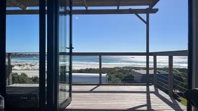 a room with a view of the beach from a house at The Red Door in Pringle Bay