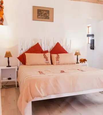 a bedroom with a large white bed with red pillows at 7th Heaven Lodge in Gordonʼs Bay