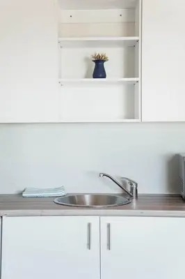 a kitchen counter with a sink and white cabinets at 7th Heaven Lodge in Gordonʼs Bay