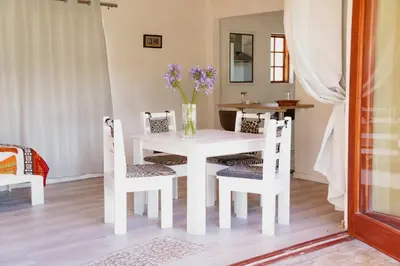 a white dining room table with chairs and a vase of flowers at 7th Heaven Lodge in Gordonʼs Bay