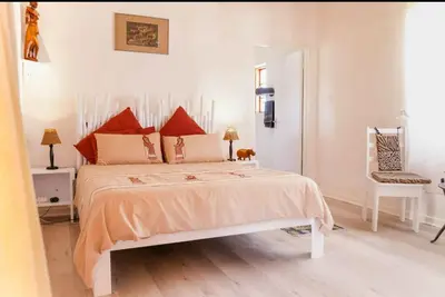 a bedroom with a bed and a chair at 7th Heaven Lodge in Gordonʼs Bay
