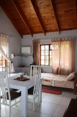 a room with a table and chairs and a bed at 7th Heaven Lodge in Gordonʼs Bay