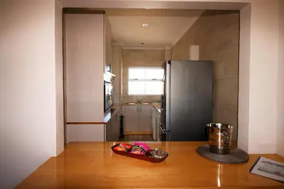 a kitchen with a refrigerator and a wooden table at Westward HO Apartment 13 in Cape Town