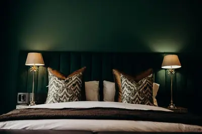 a green bedroom with a bed with two lamps at Franschhoek Boutique Hotel - Lion Roars Hotels & Lodges in Franschhoek