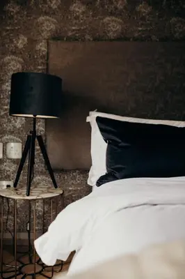 a bedroom with a bed and a black lamp at Franschhoek Boutique Hotel - Lion Roars Hotels & Lodges in Franschhoek