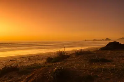 a beach at sunset with the ocean in the background at Atlantic Palms in Cape Town