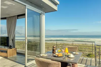 a table with food on it on a balcony with the ocean at Atlantic Palms in Cape Town