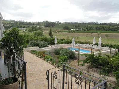 a resort with a swimming pool and a patio with umbrellas at Clos Malverne Wine Estate in Stellenbosch