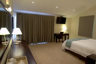 a hotel room with a bed and a desk with a desk at Clos Malverne Wine Estate in Stellenbosch