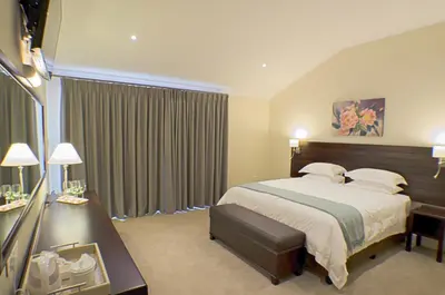 a hotel room with a bed and a desk and a window at Clos Malverne Wine Estate in Stellenbosch