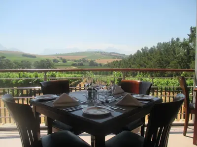 a dining table on a balcony with a view at Clos Malverne Wine Estate in Stellenbosch