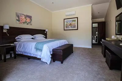 a bedroom with a large bed and a dresser in it at Clos Malverne Wine Estate in Stellenbosch