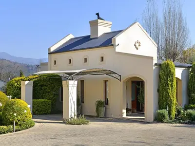 a white house with an archway in a driveway at Petit & Grande Plaisir luxury self-catering in Franschhoek