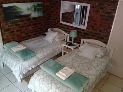 two beds sitting next to a brick wall at Coral Tree Guest Rooms in Worcester